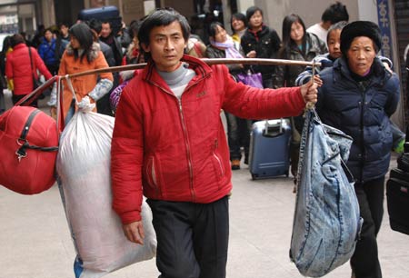 A migrant worker, with luggages on his shoulder, walks out of Hangzhou Railway Station in Hangzhou, east China's Zhejiang Province, Jan. 30, 2009. As the Spring Festival holiday is about to finish, passenger transportation of the Spring Festival started to reach the peak of return passengers.