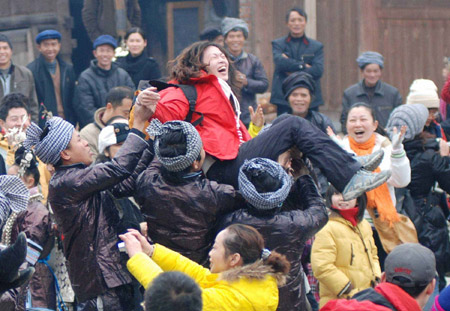 A woman visitor is tossed up to the air during a mass jubilation among local villagers and visitors across the country to admire the ethnic Dong's Ka Lau chorus, the big song of their distinguished folk vocal art among intangible cultural heritages, at the Gaozeng Township, Congjiang County, southwest China's Guizhou Province, Jan. 29, 2009.