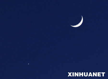 A crescent moon (R) is seen with the planet Venus in the sky over northwest China&apos;s Yinchuan city,Jan. 30, 2009.