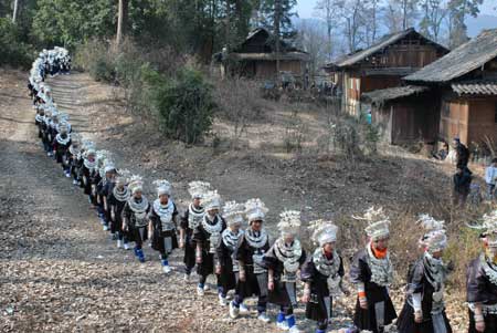 Women dressed in the costume of Miao ethnic group walk in line in the Zhanliu Village of Jianhe County, southwest China's Guizhou Province, Jan. 31, 2009. [Xinhua]