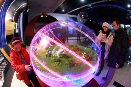 A visitor operates on trial of a celestial sphere in demonstration of the solar altitude in the earth's middle latitude areas, at the Beijing Planetarium, where wide varieties of activities are presented during the Spring Festival to lure more astronomic amatuers to go through the gamut of astronomy in Beijing, Jan. 30, 2009.