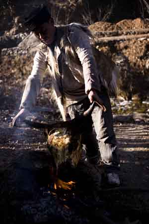 A man of the Qiang ethnic group bakes cattle's head in Qugu township of Maoxian County, southwest China's Sichuan Province, Jan. 30, 2009.