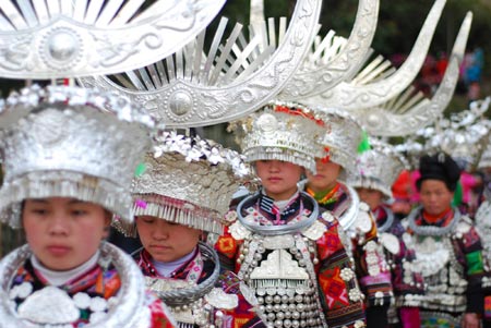 A group of ethnic Miao's young women in splendid silver headwears dance to the rhythm and beat of folk dancing of Lusheng (a reed-pipe Bamboo-cluster flute), in a brisk celebration of the lunar Spring Festival, at Nanqing Village, Danzhai County, southwest China's Guizhou Province, Jan. 31, 2009.