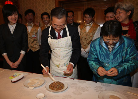 Chinese Premier Wen Jiabao (C, front) makes dumplings with staff members of the Chinese Embassy to Britain, Chinese students studying in Britain, and overseas Chinese in Britain as he visits the Chinese Embassy to Britain in London, Britain, Feb. 1, 2009. Wen is on a three-day official visit to Britain, the last leg of his week-long European tour.