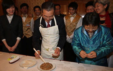 Chinese Premier Wen Jiabao (C, front) makes dumplings with staff members of the Chinese Embassy to Britain, Chinese students studying in Britain, and overseas Chinese in Britain as he visits the Chinese Embassy to Britain in London, Britain, Feb. 1, 2009. Wen is on a three-day official visit to Britain, the last leg of his week-long European tour.