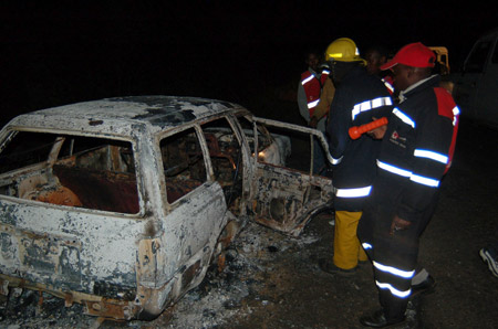 Firefighters look at a burnt car near the wreckage of an oil truck that crashed near the central Rift Valley town of Molo Jan. 31, 2009. The death toll from an oil spill blaze in central Kenya has risen to 111, making it one of the east African nation's worst disasters of recent times, police said on Sunday.(Xinhua/Reuters Photo)