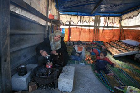 A Palestinian family who lost their home during the 22-day Israeli offensive sit by a small fire in a tent in Jabalia, northern Gaza Strip, Jan. 31, 2009.(Xinhua/Wissam Nassar)