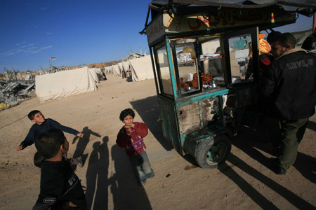 Children stand by a cart selling sweets at a camp of Palestinians who lost their homes during the 22-day Israeli offensive in Jabalia, northern Gaza Strip, Jan. 31, 2009.(Xinhua/Wissam Nassar)