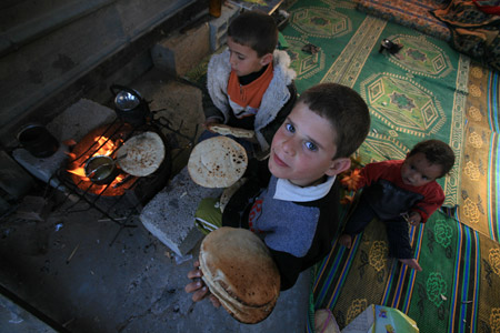 Palestinian children who lost their homes during the 22-day Israeli offensive bake cakes in a tent in Jabalia, northern Gaza Strip, Jan. 31, 2009.(Xinhua/Wissam Nassar)