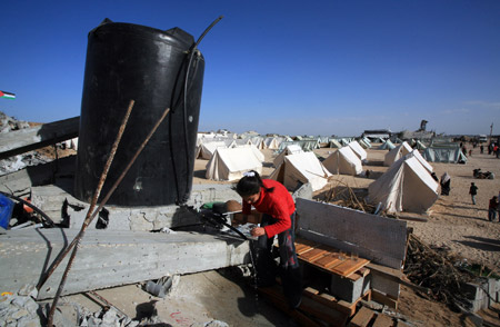 A Palestinian girl who lost her home during the 22-day Israeli offensive washes cups at a refugee camp in Jabalia, northern Gaza Strip, Jan. 31, 2009. (Xinhua/Wissam Nassar)