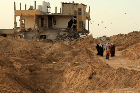 Palestinians walk past a destroyed house at a refugee camp in Jabalia, northern Gaza Strip, Jan. 31, 2009.(Xinhua/Wissam Nassar)