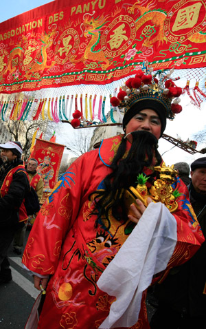 A man dressed as traditional Chinese God of Wealth picks a "golden bull" during a Chinese Lunar New Year celebration at a China Town in Paris, capital of France, on Feb. 1, 2009. (Xinhua/Zhang Yuwei)