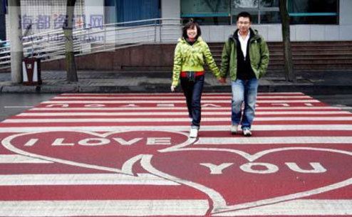 A couple are crossing over a 'Love zebra crossing' in Chengdu, Sichuan on Sunday, February 1, 2009. The red-ground zebra crossing, first such work in China, was painted with words 'I Love You' and two linked hearts. The 'red carpet' was created to send blessings to local couples, and to remind people of traffic regulations. [Photo:hdzxw.com]