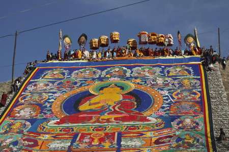 Ethnic Tibetan monks display a giant &apos;thangka&apos;, a sacred painting on cloth on a hill outside a monastery in Tongren, northwest China&apos;s Qinghai province Monday, Feb. 2, 2009. Local Tibetan monks and pilgrims gather to celebrate Monlam, or Great Prayer Festival, one of the most important festivals in Tibetan Buddhism. (Photo: China Daily) 