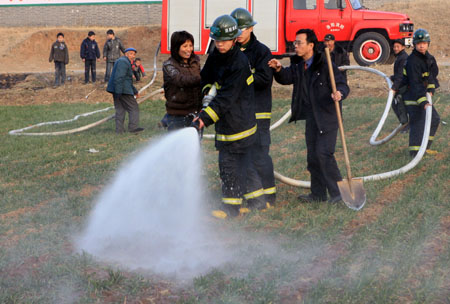 Firemen help irrigate the wheat field in Luoyang, a city in central China's Henan Province, on Feb. 4, 2009. Henan, China's major grain producer, issued a red alert for drought on Jan. 29. The provincial meteorological bureau said the drought is the worst since 1951. The drought has affected 63 percent of the province's 5.26 million hectares of wheat. [Zhang Xiaoli/Xinhua]