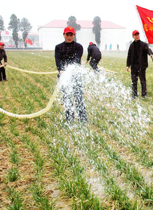 People irrigate the wheat field in the Wolong District of Nanyang, a city in central China's Henan Province, on Feb. 4, 2009. Henan, China's major grain producer, issued a red alert for drought on Jan. 29. The provincial meteorological bureau said the drought is the worst since 1951. The drought has affected 63 percent of the province's 5.26 million hectares of wheat. [Xiong Yunbin/Xinhua]