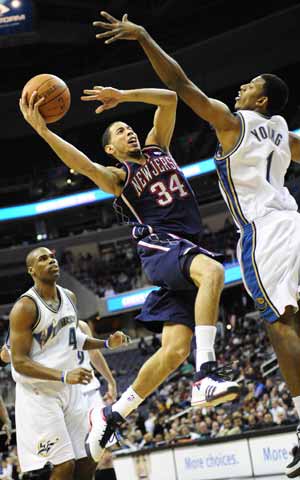 New Jersey Nets' Devin Harris (C) goes up to shoot past Nick Young of Washington Wizards during their NBA game held in Washington, the United States, February 4, 2009.New Jersey Nets won 115-88. 