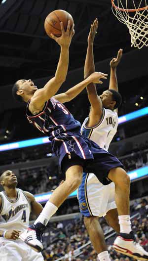 New Jersey Nets' Devin Harris (C) goes up to shoot past Nick Young of Washington Wizards during their NBA game held in Washington, the United States, February 4, 2009. New Jersey Nets won 115-88. 