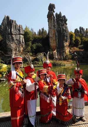 Kids dressed in local ethnic costumes pose for a group photo in front of the Stone Forest near Kunming, capital of southwest China's Yunnan Province, Feb. 4, 2009.(Xinhua/Lin Yiguang) 