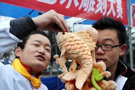 A chef sculpts vegetables into a carp during a food carving competition in Qingdao, east China's Shandong Province, Feb. 4, 2009.