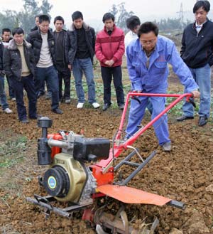 A technician shows how to operate a ploughing machine at Renhe Village of Baixi Township in Yibin County, southwest China's Sichuan Province, Feb. 2, 2009. As the spring ploughing starts in south China, technical trains are given to the farmers there to help them raise efficiency.