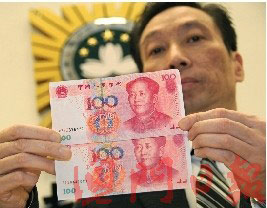 A Macau police officer compares an authentic 100 yuan banknote (top) with a counterfeit (below) on February 5, 2009. The security thread is less pronounced on the counterfeit note. [Photo: Macao Daily] 