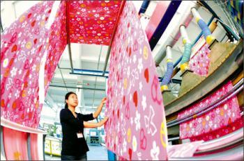 A worker checks the cloth at a workshop in Zhangjiagang City, north China's Hebei Province October 22, 2008. China will increase the tax rebate rate for textile and garment exports from 14 percent to 15 percent. [china.com] 
