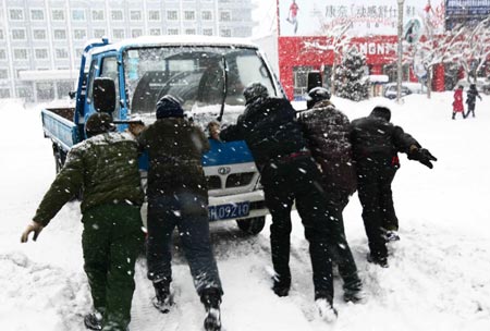 Residents push a conked truck in snow in Altay area in northwest China's Xinjiang Uygur Autonomous Region Feb. 5, 2009. A heavy snowfall hit Altay on Thursday. Local government has sent over 100 workers to the pasturing area to help herdsmen fight against the chilliness. [Xinhua] 