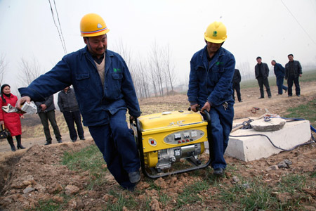 Workers of a power company install a generator to provide power for irrigating fields in Baizhuang Village of Baofeng County, central China's Henan Province, Feb. 5, 2009. [Yan Ruipeng/Xinhua]