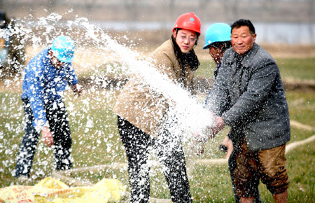 Workers of a power company help a farmer to irrigate the field in Wuhe County, east China's Anhui Province, Feb. 5, 2009. [Yan Ruipeng/Xinhua] 