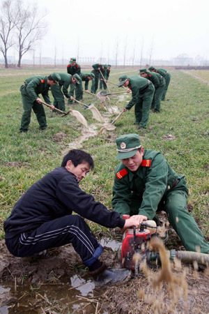 Soldiers of armed police force help a farmer to irrigate his field in Huainan, east China's Anhui Province, Feb. 5, 2009. [Yan Ruipeng/Xinhua] 