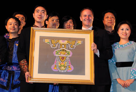 Performers of the Wu Opera Troupe from China's Zhejiang Province presents a craftwork with a logo of ox to New Zealand's Prime Minister John Key (3rd,R), who was born in the Year of the Ox, as a celebration for the Chinese Lantern Festival opened in Auckland, New Zealand, Feb. 5, 2009. [Xinhua]