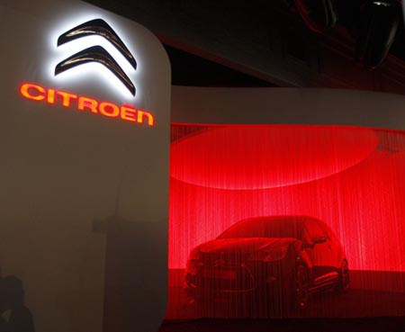 A new concept car is about to be unveiled next to the new Logo of French car maker Peugeot-Citroen during a news conference in Paris, February 5, 2009. 