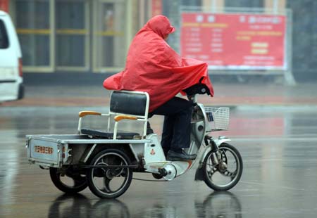 A resident rides a tricycle in rain in Heze, a city in east China's Shandong Province, Feb. 8, 2009. A rainfall hit some areas of Shandong, partially easing the ongoing drought plaguing the province. [Photo: Xinhua]