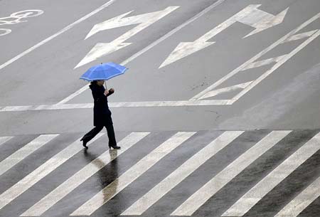 A resident walks in rain on Ma'anshan Road in Jinan, capital city of east China's Shandong Province, Feb. 8, 2009. A rainfall hit some areas of Shandong, partially easing the ongoing drought plaguing the province. [Photo: Xinhua]