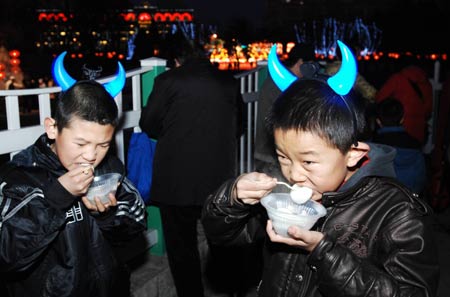 Two kids enjoy rice balls in a Lantern Festival catering activity held in Dalian, a coastal city of northeast China's Liaoning Province, Feb. 7, 2009. Over 1,000 visitors ate rice balls together at the Laodong Park in Dalian on Saturday. [Liu Debin/Xinhua]