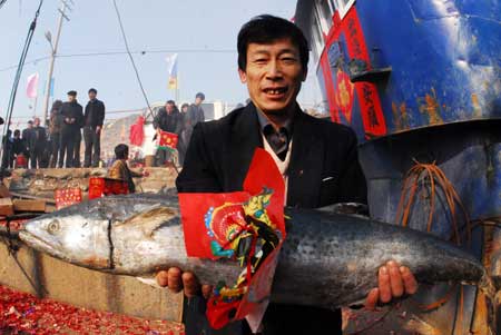 A fisherman offers a big fish as sacrifice on Fishing Lamp Day in the fishing harbor of Chuwang Village in Yantai city of east China's Shandong Province, Feb. 7, 2009.[Photo: Xinhua]