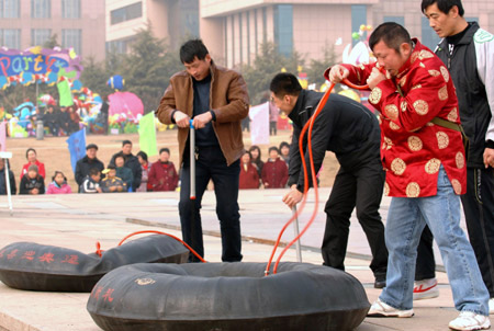 Zhang Zhenghui, a folk artist, blows a tyre by his nose, competing with two guys blowing with inflators during a folk art festival held in Qingdao, east China&apos;s Shandong Province, Feb. 5, 2009. Folk artists from more than 40 troupes showed up their exclusive skills during the one-week festival opened on Wednesday. [Photo: Xinhua]
