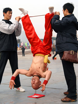 Li Xin, a folk artist, stands on his head against a nail during a folk art festival held in Qingdao, east China's Shandong Province, Feb. 5, 2009. [Photo: Xinhua] 