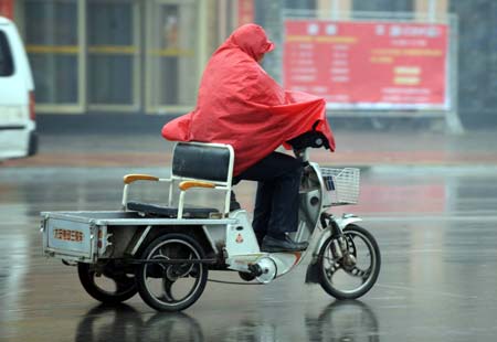 A resident rides a tricycle in rain in Heze, a city in east China's Shandong Province, Feb. 8, 2009. A rainfall hit some areas of Shandong, partially easing the ongoing drought plaguing the province. (Xinhua/Fan Changguo)