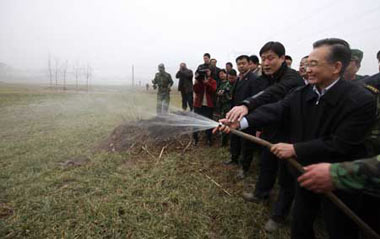 Chinese Premier Wen Jiabao (Front) waters wheat at Donggao Village of Hongchang Township in Yuzhou City, central China's Henan Province, Feb. 7, 2009. Premier Wen inspected the anti-drought work in Henan, one of China's key wheat producing regions, on Feb. 7-8.