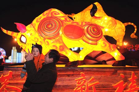 People pose for photos in front of an illuminated ox-shaped lamp during the lantern fair in Hangzhou, capital of east China's Zhejiang Province, Feb. 8, 2009. The Chinese traditional Lantern Festival falls on the 15th day of the first month of the Chinese lunar calendar, or Feb. 9 this year. (Xinhua/Tan Jin)