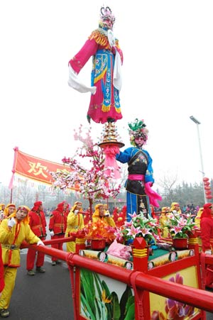 A local folklore Xin Zi promenade, in which teenager performers garbed as popular theatric or legendary figures towering high on the floral sedans, are on parade for the lantern festival jollification, on the avenue of Zhoucun District, Zibo City, east China's Shandong Province, Feb. 8, 2009. 