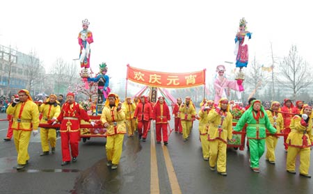 A local folklore Xin Zi promenade, in which teenager performers garbed as popular theatric or legendary figures towering high on the floral sedans, is on parade for the lantern festival jollification, on the avenue of Zhoucun District, Zibo City, east China's Shandong Province, Feb. 8, 2009. (Xinhua/Dong Naide) 