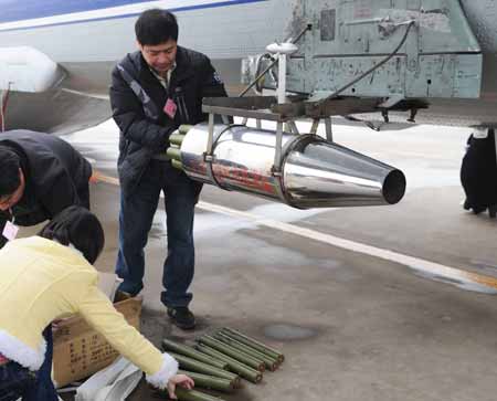 Workers equip the aircraft with catalystic silver iodide for the mission of artificial rainfall operations at Xinzheng International Airport in Zhengzhou, capital of central China's Henan Province, Feb. 8, 2009. A couple of 'Transport 7' aircraft of China's Air Force performed artificial rainfall operations in Huaibei of east China's Anhui Province, and Luoyang and Kaifeng of central China's Henan Province separately to relieve local drought on Sunday.(Xinhua Photo)