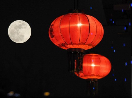 A full moon is seen beside red lanterns on the night of the Lantern Festival in Shenyang, northeast China's Liaoning province February 9, 2009. The moon on Monday night is supposed to look the biggest and brightest in all the Lantern Festivals since 1957. [Photo: Xinhua] 