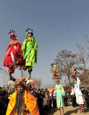 Child performers are garbed and carried high on the shoulders of elders during a local folk parade for the lantern festival celebration at a village in Luoyang City, central China's Henan Province, Feb. 9, 2009.