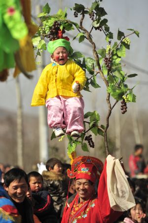 A child performer cries out of fear when he is garbed and carried high on the shoulders of an elder during a local folk parade for the lantern festival celebration at a village in Luoyang City, central China's Henan Province, Feb. 9, 2009.