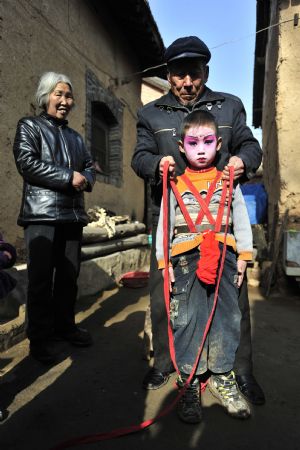 A villager binds a child performer on a supporting pole before being garbed and carried high on the shoulders of elders during a local folk parade for the lantern festival celebration at a village in Luoyang City, central China's Henan Province, Feb. 9, 2009.