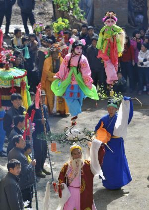 Child performers are garbed and carried high on the shoulders of elders during a local folk parade for the lantern festival celebration at a village in Luoyang City, central China's Henan Province, Feb. 9, 2009.